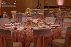 the tables are set up for a formal function with pink linens and gold place settings