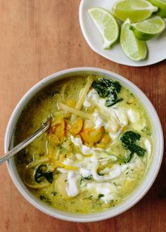 a white bowl filled with soup next to sliced limes on top of a wooden table