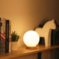 a white light sitting on top of a wooden shelf next to a potted plant