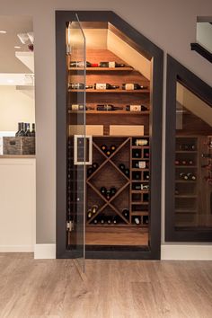 a wine cellar in the corner of a room next to a stair case with glass doors