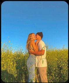 a man and woman kissing in a field of wildflowers under a blue sky