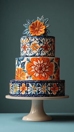 a multi - tiered cake decorated with orange and blue flowers