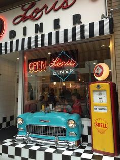 an old car parked in front of a diner