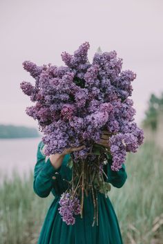 a woman in a green dress holding purple flowers