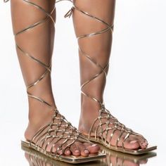 Flat Sandal In Gold Features A Vegan Leather Construction, A Flat Sole, A Strappy Lace Up Silhouette, An Open Square Toe, And A Wide Basket Woven Upper. Fit And Details Approx. Measured From A Women’s Size 8: - Open Toe - 35” Lace Length - Strappy Upper - Lace-Up Fit - Imported Gold Strappy Lace-up Sandals, Gold Ankle Strap Lace-up Sandals For The Beach, Gold Lace-up Sandals With Round Toe For Beach, Gold Lace-up Sandals For Beach, Gold Open Toe Lace-up Beach Sandals, Gold Round Toe Lace-up Sandals For Vacation, Gold Strappy Sandals For Summer, Gold Lace-up Sandals With Round Toe For Vacation, Gold Strappy Lace-up Sandals For Vacation