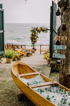 a wooden boat filled with lots of bottles next to a tree near the ocean and beach