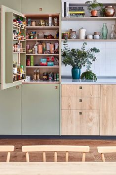 a kitchen with wooden cabinets and shelves filled with food on top of each shelf, next to a dining room table