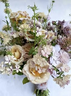 a bouquet of flowers sitting on top of a white tablecloth next to a wall