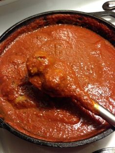 a pot filled with red sauce on top of a stove