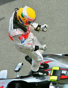 a man riding on the back of a motorcycle down a race track next to a car