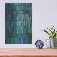 a clock sitting on top of a wooden table next to a potted green plant