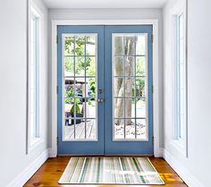 a blue front door with two windows and a rug on the floor in front of it