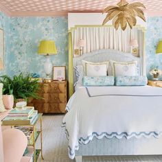 a bedroom decorated in pastel colors with blue and white wallpaper, gold accents