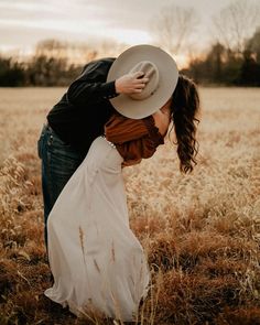 a woman in a white dress and hat bending over to kiss her man's forehead