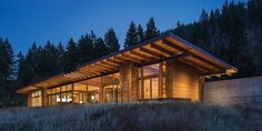 a house that is sitting on top of a hill in the woods at night with its lights on