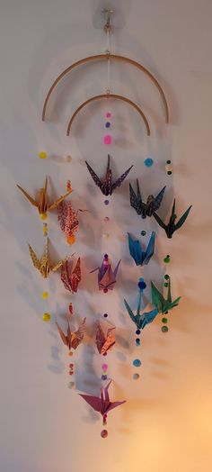 there are many different colored paper birds hanging from the ceiling