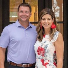 a man and woman standing in front of a door smiling at the camera with red earrings on their ears