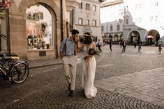 a man and woman are walking down the street with flowers in their hands while holding each other's hand