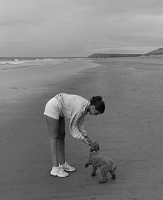 the woman is playing with her dog on the beach