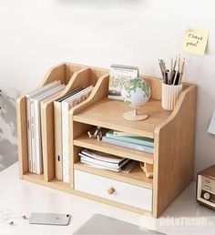 a wooden desk with some books and pencils on top of it next to a clock