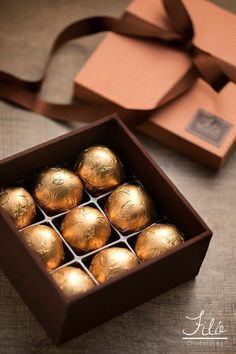 a box filled with chocolates sitting on top of a table next to a brown ribbon