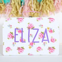 a white suitcase with pink flowers on it and the word elizabeth written in purple letters