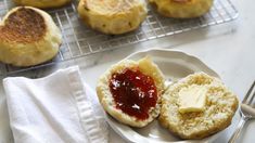 biscuits with jam and butter on a plate next to silverware, fork and napkin