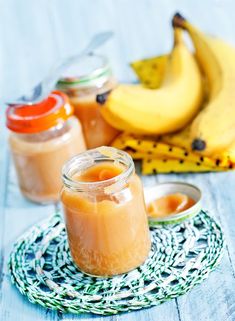 two jars filled with food sitting on top of a table next to bananas and other foods