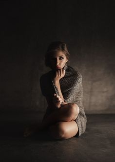 a woman sitting on the floor with her hand under her chin