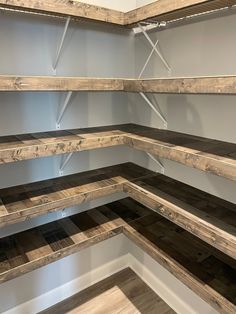 an empty room with shelves made out of wooden planks and metal brackets on the wall