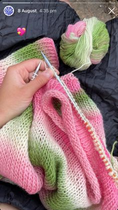 someone is knitting yarn on top of a pink and green blanket with a crochet hook