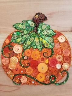 a pumpkin made out of buttons on a wooden board