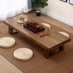 a wooden table sitting on top of a rug next to two baskets and a potted plant