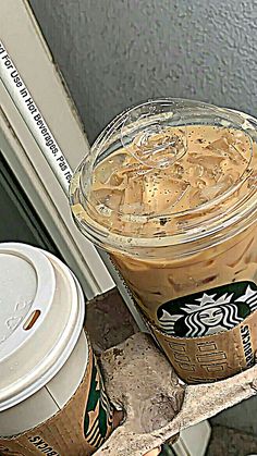 two cups of coffee sitting on top of each other next to a window sill