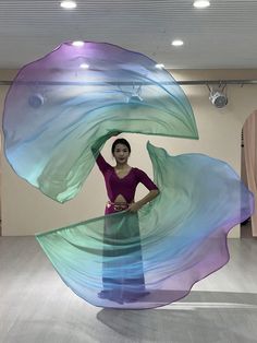 a woman is standing in front of a large piece of art that looks like an ocean wave