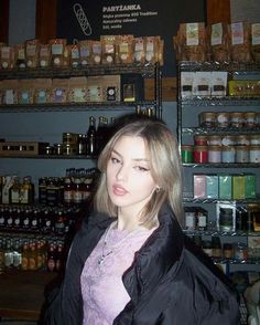 a woman standing in front of a shelf filled with spices