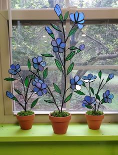 three potted plants sitting on top of a window sill in front of a window