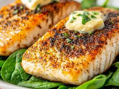 two fish fillets with butter and spinach on a plate