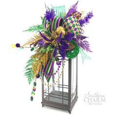 a purple and green flower arrangement in a birdcage for mardi gras