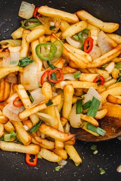 french fries with peppers and onions in a frying pan