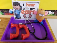 a purple tray topped with toys and a sign that says i hear with my ears