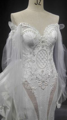 the back of a wedding dress on display in a store window, with its veil draped over it