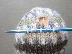 a knitted hat with a crochet stitch on it and a knitting needle in the middle