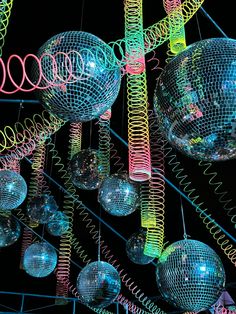 several disco balls hanging from the ceiling with colored lights on them and colorful spirals in the air