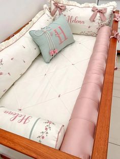 a baby crib with pink and blue pillows on it