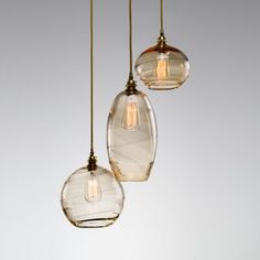 three clear glass globes hanging from a ceiling fixture with one light bulb turned on