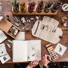 a person is working on an art project at a table with many other items and supplies