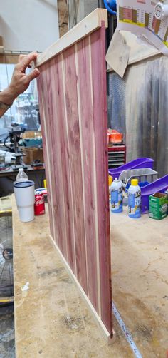 a person holding up a piece of wood to the side of a door that is being built