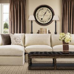 a living room filled with furniture and a large clock on the wall above it's windows