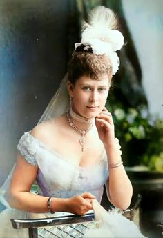 an old photo of a woman wearing a wedding dress and veil with feathers on her head